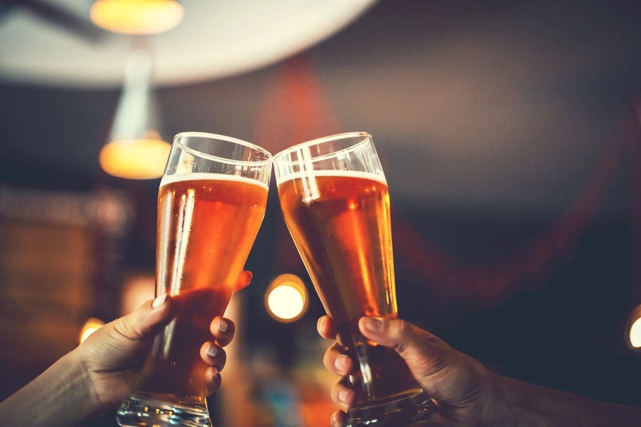 Two people holding beer glasses in their hands.