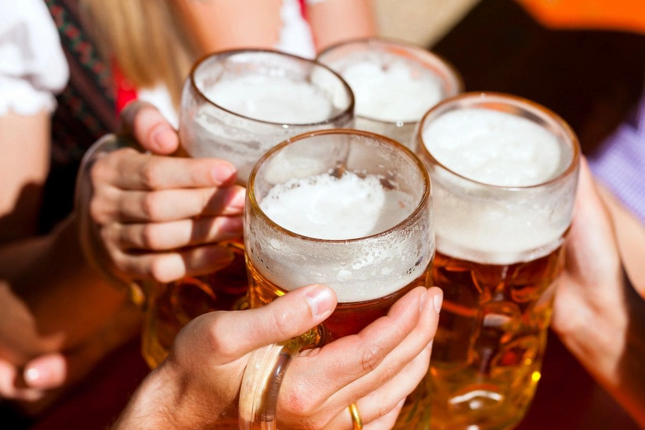 A group of people holding beer glasses in their hands.