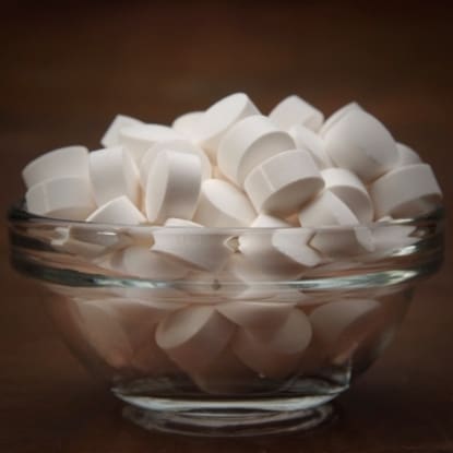 A glass bowl full of white sugar cubes.