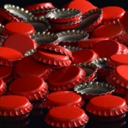 Pile of red bottle caps on black background.