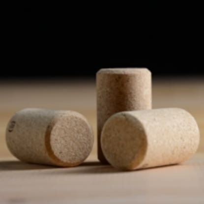 Three cork stoppers on a wooden surface.