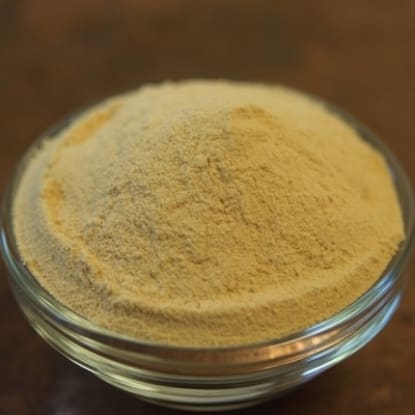 A bowl of yellow powder on top of a table.