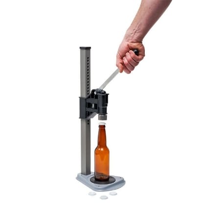 Hand capping a bottle with a capper.