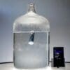 Glass jug with water and smartphone display.